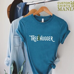 May include: A teal blue t-shirt with the text "Tree Hugger" in white with a small green tree graphic above the text.