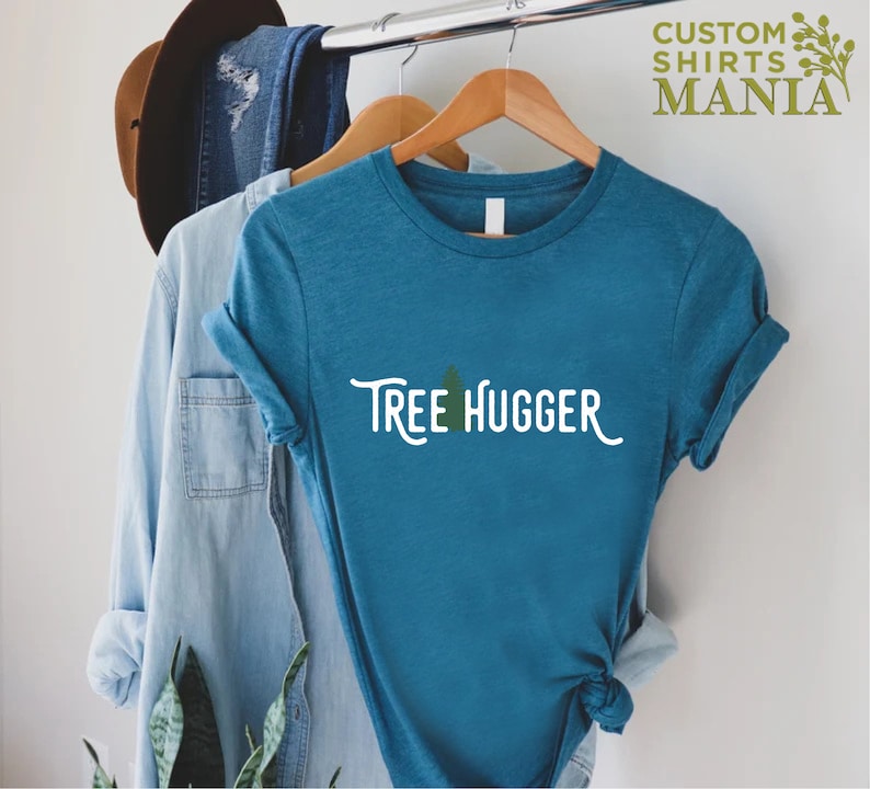 May include: A teal blue t-shirt with the text "Tree Hugger" in white with a small green tree graphic above the text.