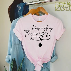 May include: Pink t-shirt with black text that reads "Respiratory Therapist" and a stethoscope with a heart graphic.