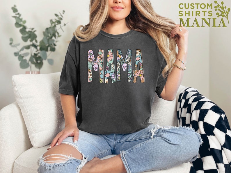 a woman sitting on a couch wearing a t - shirt that says mama
