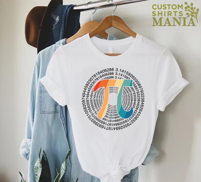 Może przedstawiać: Biały t-shirt z wzorem w kształcie tęczy, przedstawiającym stałą matematyczną pi (&pi;) i cyfry pi w układzie kołowym.