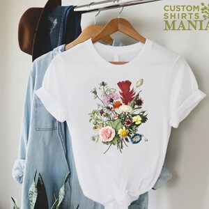 a white t - shirt with a bouquet of flowers on it