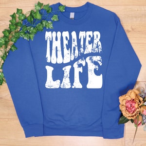 May include: Royal blue sweatshirt with a white distressed graphic that says "Theater Life" in a retro font.