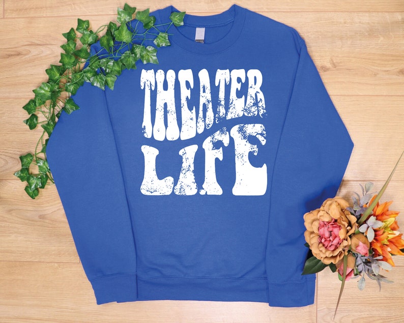 May include: Royal blue sweatshirt with a white distressed graphic that says "Theater Life" in a retro font.