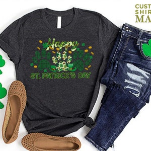 May include: A dark grey t-shirt with a green shamrock and paw print design. The text "Happy St. Patrick's Day" is printed on the shirt.