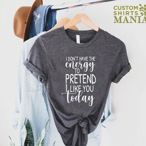 May include: A dark grey t-shirt with white text that reads "I don't have the energy to pretend I like you today".