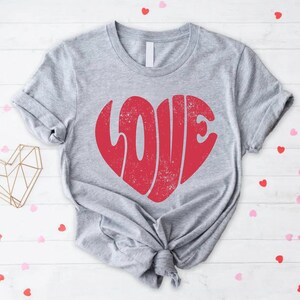 May include: A gray t-shirt with a red heart-shaped graphic that says "LOVE" in a vintage style font.