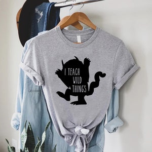 May include: A gray t-shirt with a black silhouette of a monster and the text "I teach wild things".