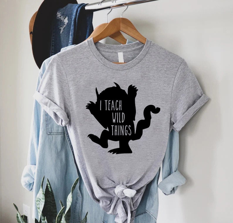 May include: A gray t-shirt with a black silhouette of a monster and the text "I teach wild things".