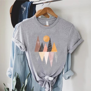 a t - shirt hanging on a rack next to a plant