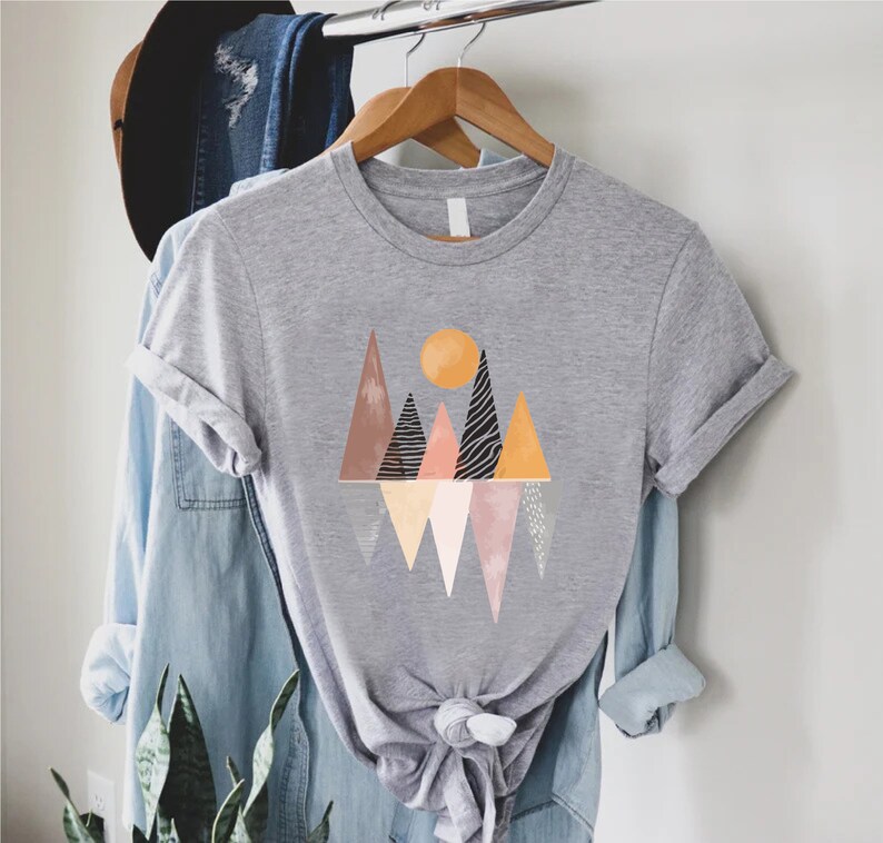 a t - shirt hanging on a rack next to a plant