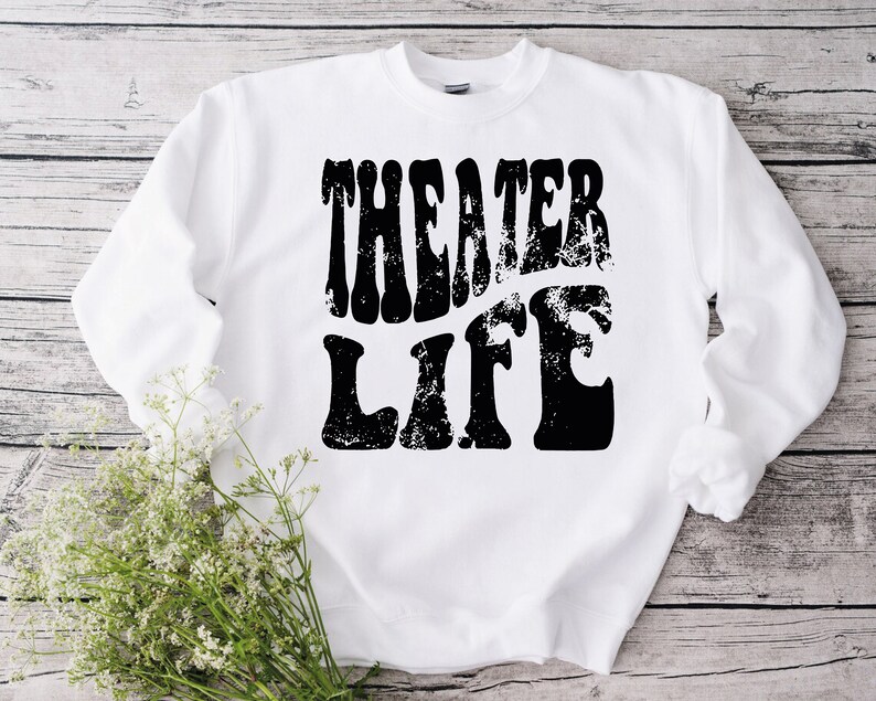 May include: White sweatshirt with black text that reads "Theater Life" in a retro, distressed font.
