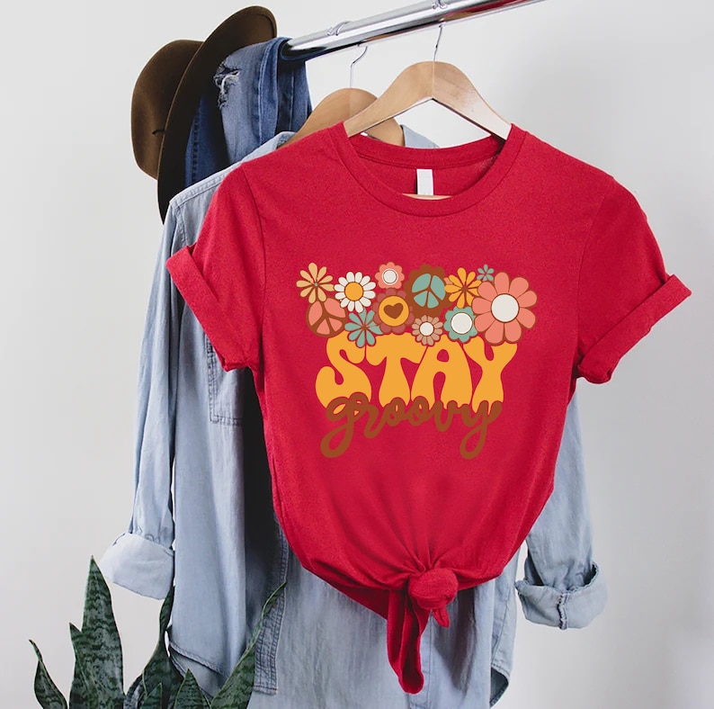 May include: Red t-shirt with a graphic of flowers and peace signs, and the text "Stay Groovy" in a retro font.