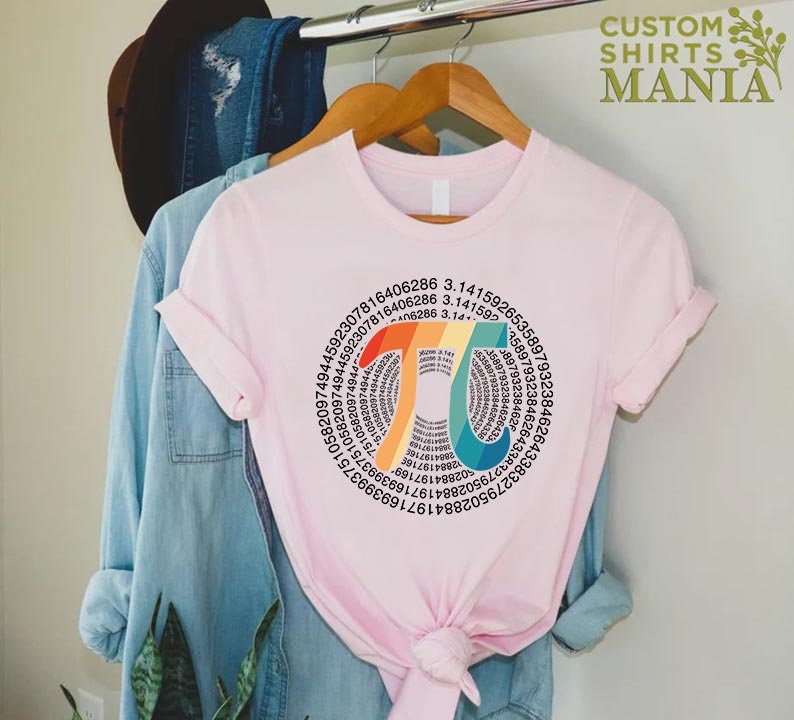 Może przedstawiać: R&oacute;żowy T-shirt z tęczowym symbolem pi. Symbol pi składa się z pierwszych 100 cyfr pi. Tekst "Pi = 3,14..." jest napisany wewnątrz symbolu pi.