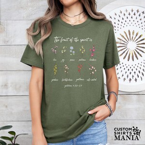 a woman wearing a green t - shirt with flowers on it