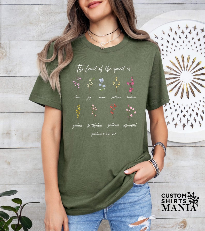 a woman wearing a green t - shirt with flowers on it