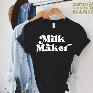 May include: Black t-shirt with white text that reads "Milk Maker" in a retro font.