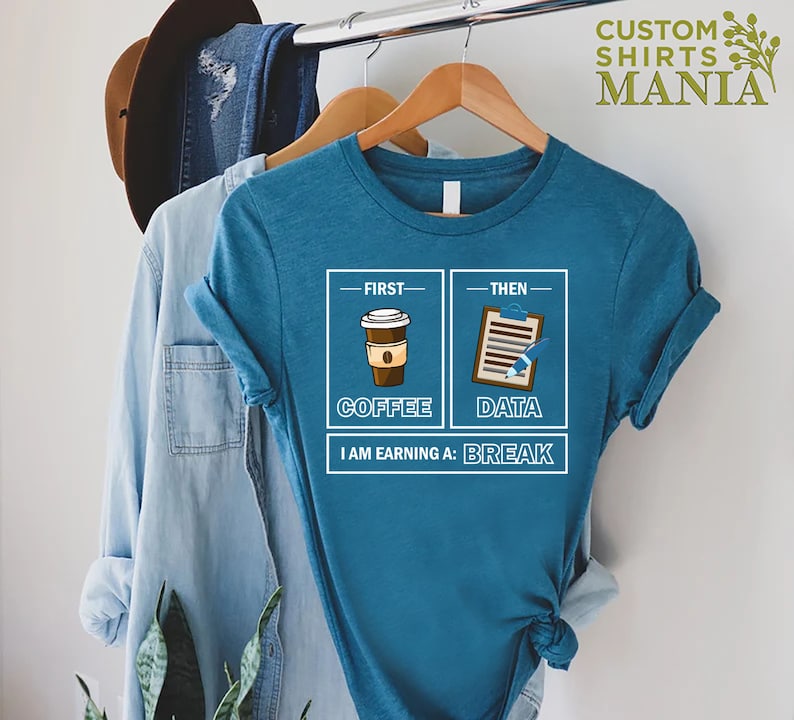 May include: A teal blue t-shirt with a graphic design of a coffee cup and a clipboard with the text "First - Coffee, Then - Data, I am earning a: Break".