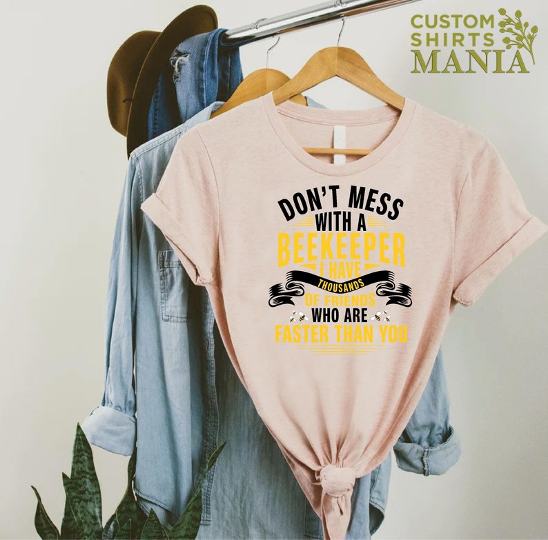 May include: A pink t-shirt with a black and yellow graphic that says "Don't mess with a beekeeper I have thousands of friends who are faster than you".