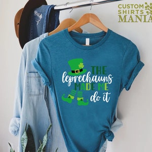 May include: A teal blue t-shirt with a green leprechaun graphic and the text "The Leprechauns Made Me Do It".