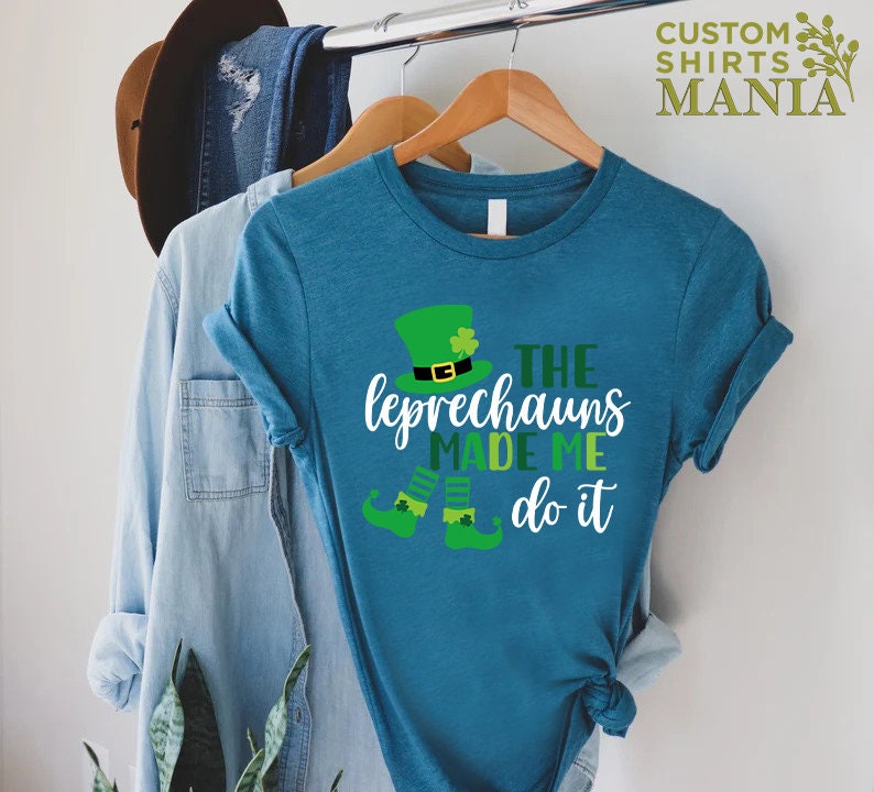 May include: A teal blue t-shirt with a green leprechaun graphic and the text "The Leprechauns Made Me Do It".