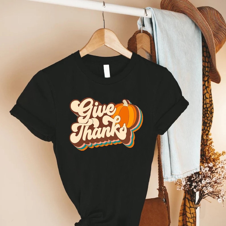 a t - shirt that says give thanks hanging on a rack