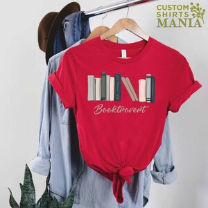 May include: Red t-shirt with a graphic of a stack of books and the text "Booktrovert".