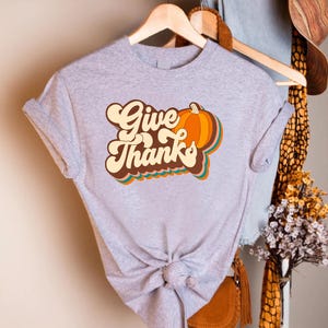 a t - shirt that says give thanks hanging on a rack