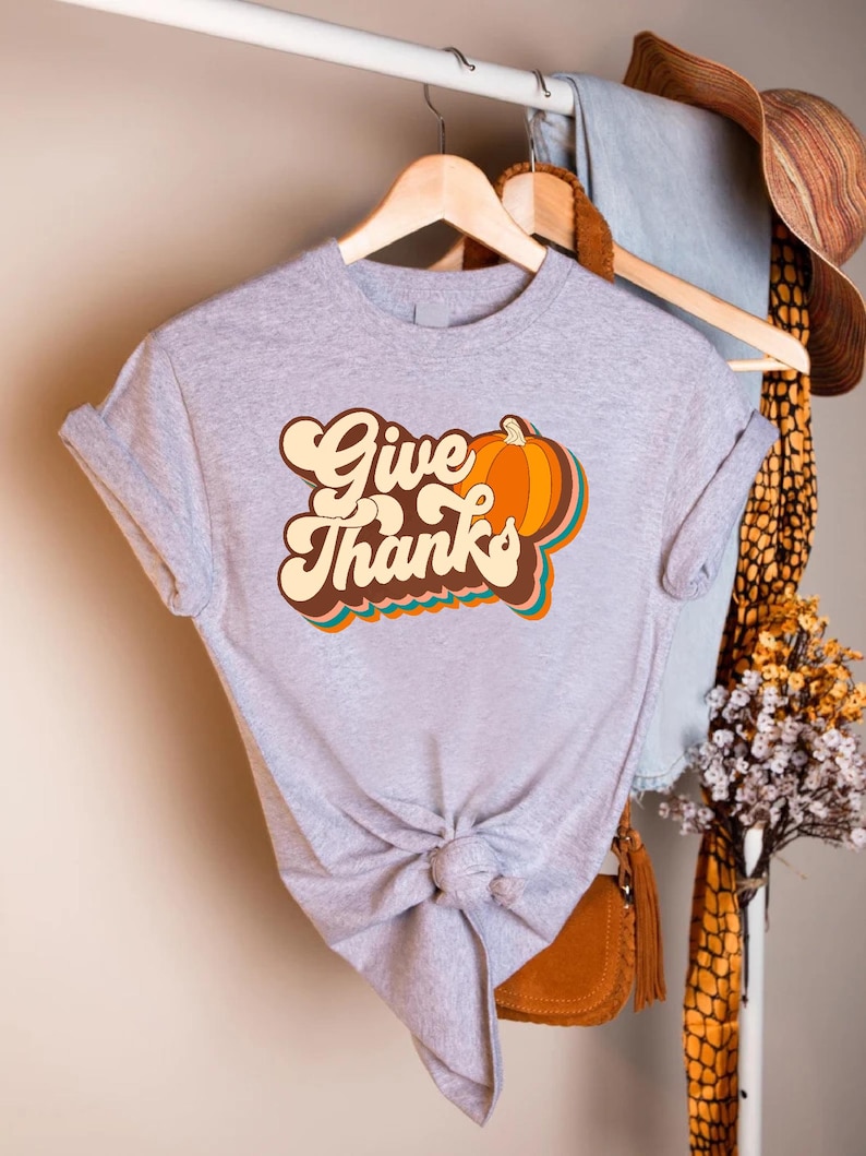a t - shirt that says give thanks hanging on a rack