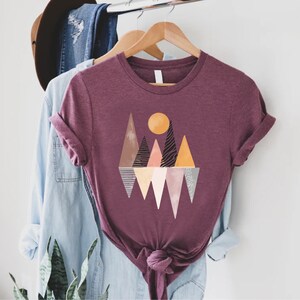 a t - shirt hanging on a rack next to a hat