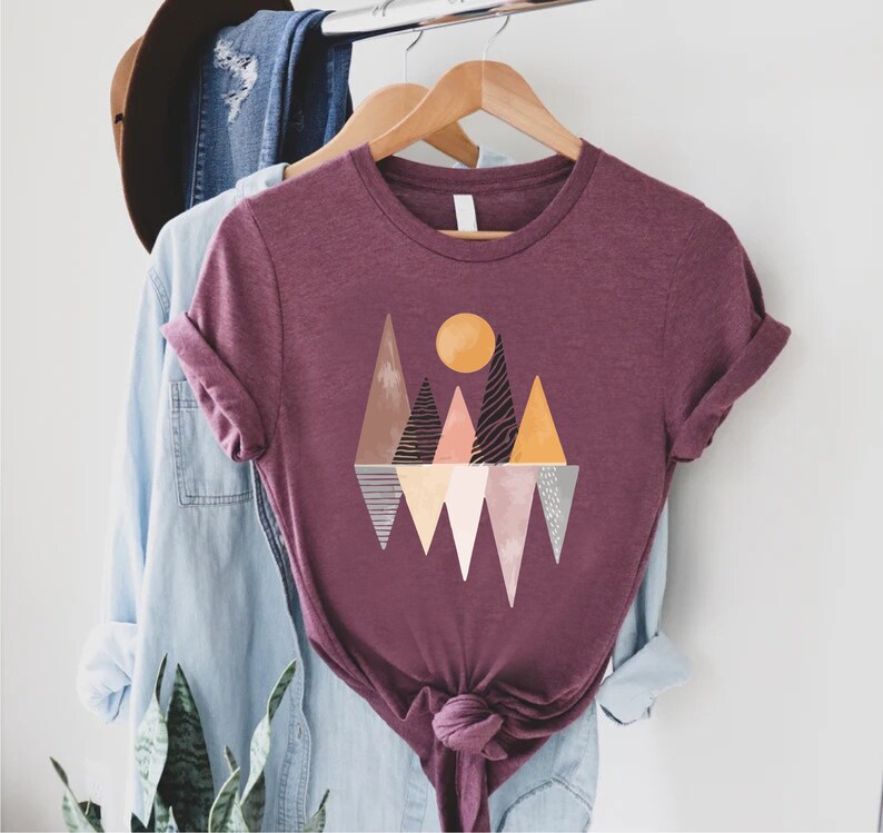 a t - shirt hanging on a rack next to a hat