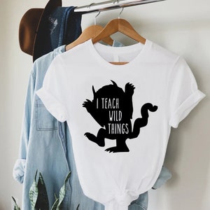 May include: White t-shirt with a black silhouette of the character from the book "Where the Wild Things Are" and the text "I teach wild things".