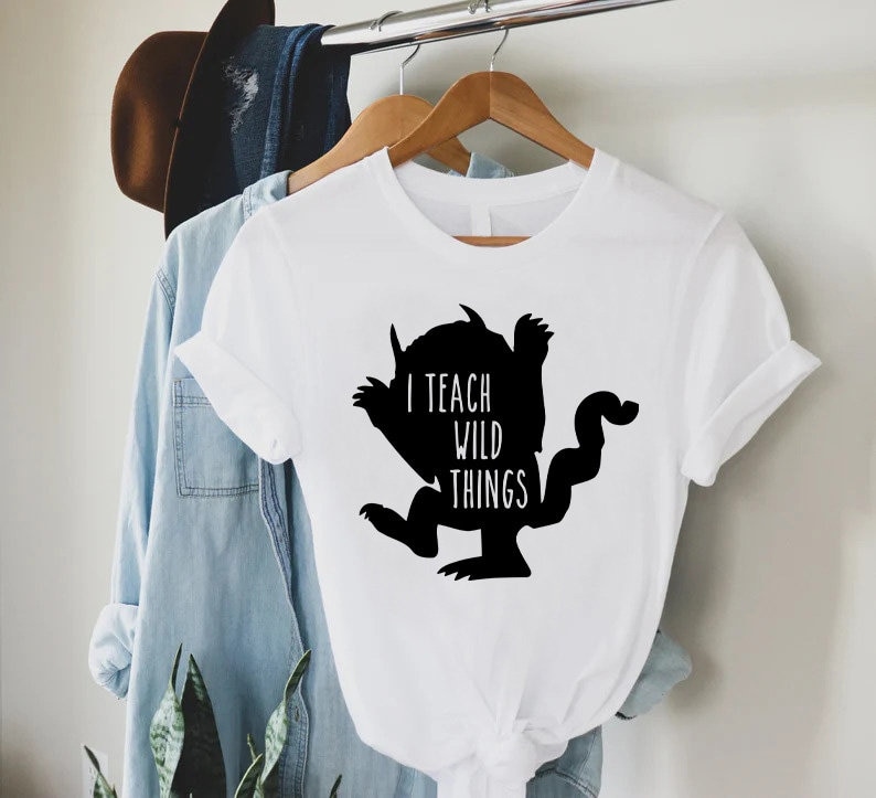 May include: White t-shirt with a black silhouette of the character from the book "Where the Wild Things Are" and the text "I teach wild things".