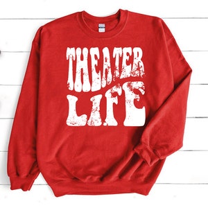 May include: Red sweatshirt with white text that reads "Theater Life" in a retro font.