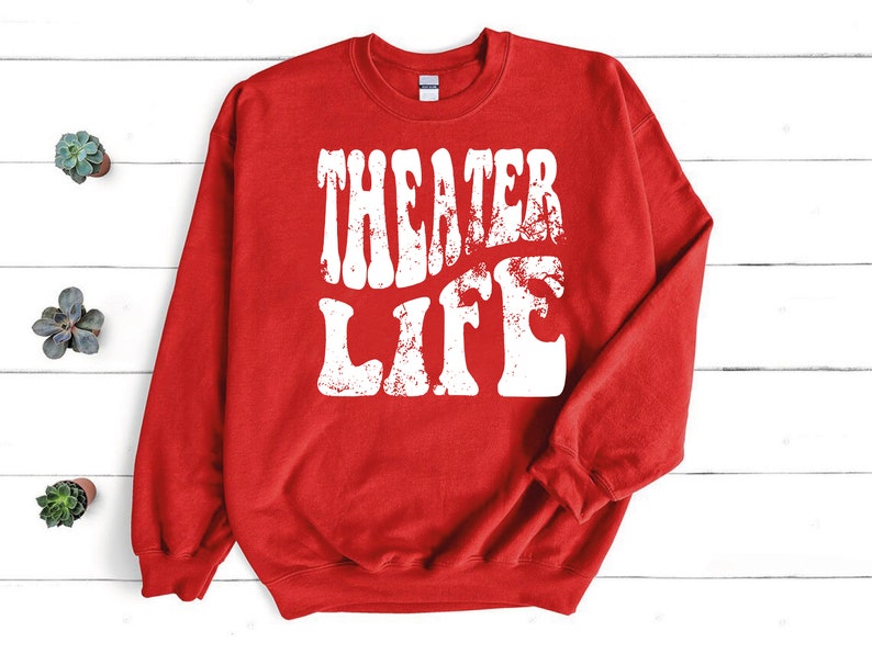 May include: Red sweatshirt with white text that reads "Theater Life" in a retro font.