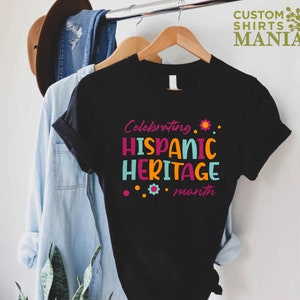 May include: Black t-shirt with the text "Celebrating Hispanic Heritage month" in colorful letters with a flower design.