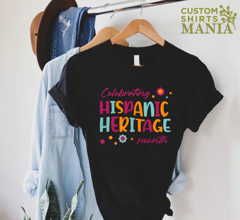 May include: Black t-shirt with the text "Celebrating Hispanic Heritage month" in colorful letters with a flower design.