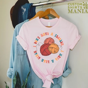 May include: Pink t-shirt with a graphic of yarn balls and the text "I don't have a problem I have a yarn stash".