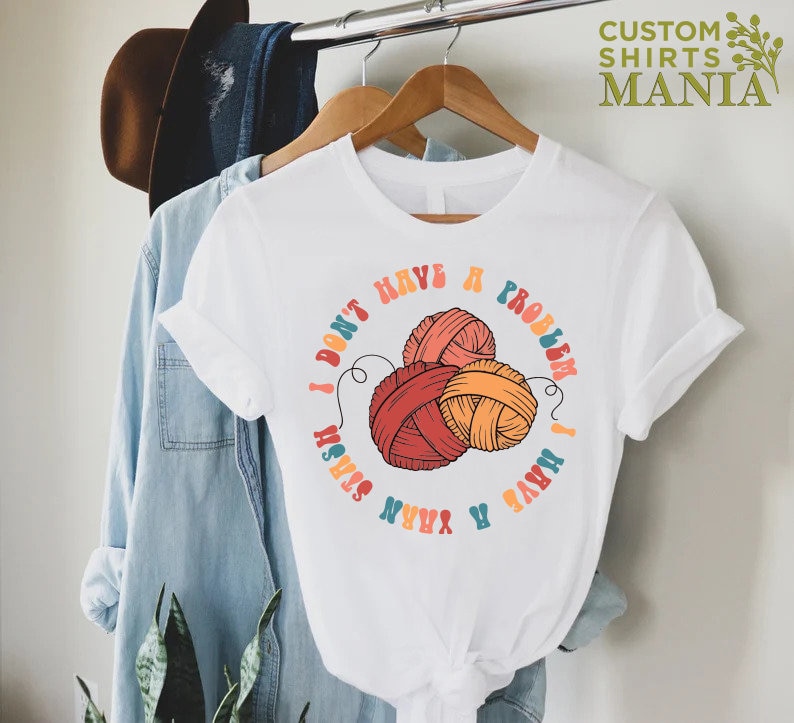 May include: White t-shirt with a colorful graphic of yarn balls and the text "I don't have a problem I have yarn stash".