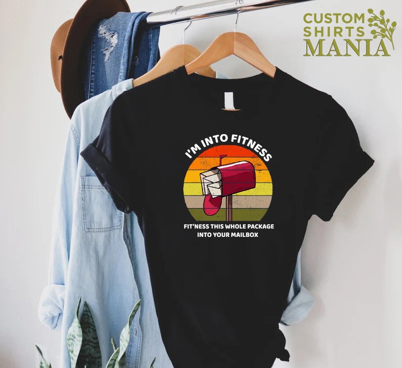 May include: A black t-shirt with a vintage-style graphic of a red mailbox with the text "I'm into fitness. Fit'ness this whole package into your mailbox."