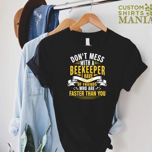 May include: Black t-shirt with yellow text that reads "Don't mess with a beekeeper I have thousands of friends who are faster than you".