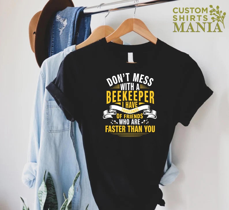 May include: Black t-shirt with yellow text that reads "Don't mess with a beekeeper I have thousands of friends who are faster than you".