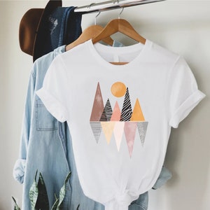 a t - shirt hanging on a clothes rack next to a plant