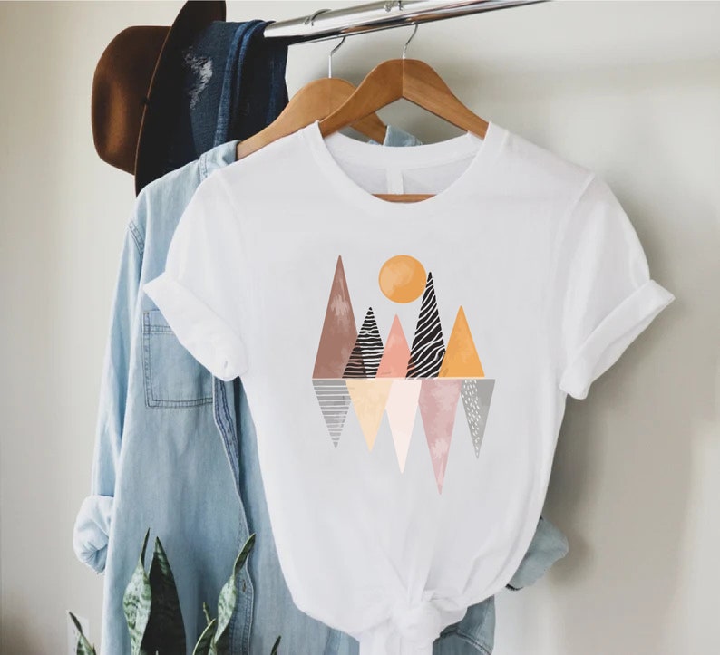 a t - shirt hanging on a clothes rack next to a plant