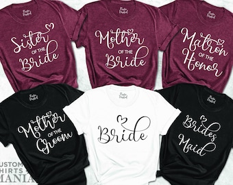 May include: Six t-shirts with different wedding party titles printed on them. The shirts are in maroon, black, and white. The text on the shirts reads "Sister of the Bride", "Mother of the Bride", "Matron of Honor", "Mother of the Groom", "Bride", and "Brides Maid".