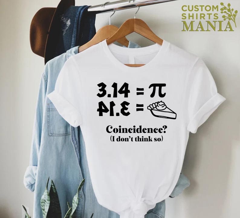 K&ouml;nnte beinhalten: Wei&szlig;es T-Shirt mit schwarzem Text, der "3.14 = &pi; &pi;.&epsilon; =" lautet, mit einer Tortendarstellung. Der Text darunter lautet "Zufall? (Ich glaube nicht)"