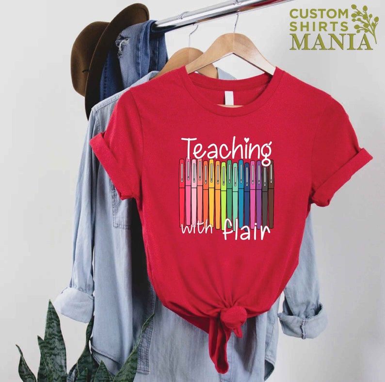May include: Red t-shirt with the text "Teaching with flair" and a graphic of colorful markers.