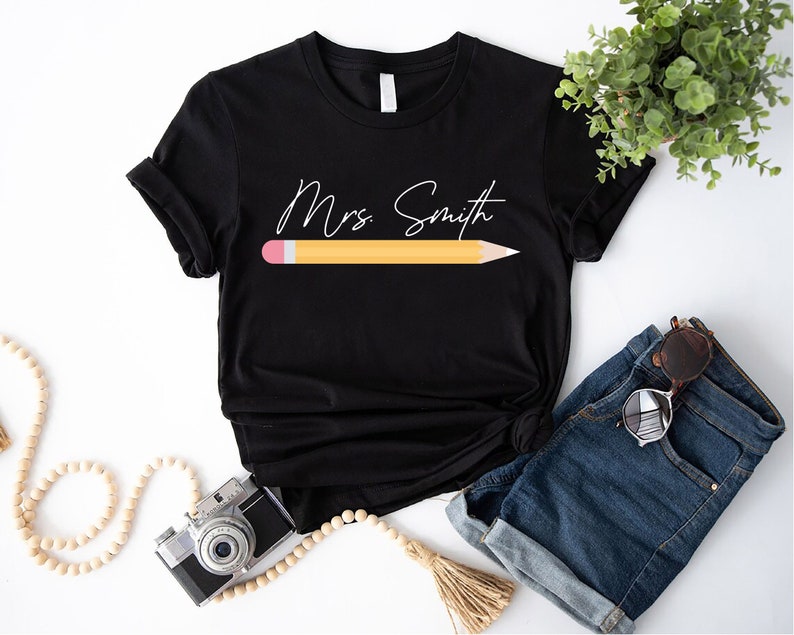 a t - shirt with a pencil and a camera next to it