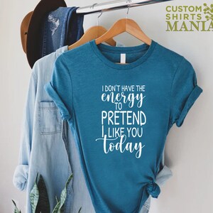 May include: A teal blue t-shirt with the text "I don't have the energy to pretend I like you today" in white.