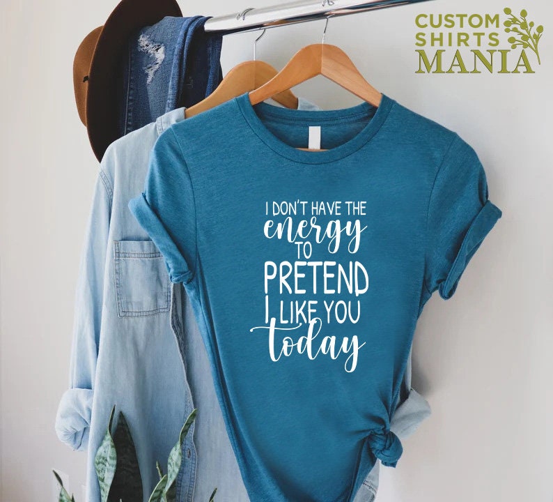 May include: A teal blue t-shirt with the text "I don't have the energy to pretend I like you today" in white.